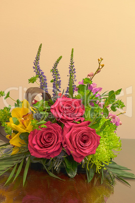 Pink roses, yellow cymbidium , green mums, and palms in a tropic