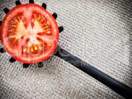 Half tomato on a black plastic kitchen spoon.