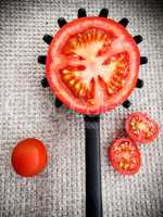 Half tomato on a black plastic kitchen spoon.