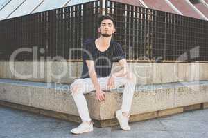 Stylish young man with a haircut in fashion  sitting in the stre