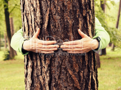 Young man hugs a tree