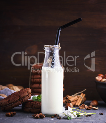 one full glass bottle with milk and a black straw
