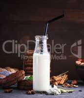 one full glass bottle with milk and a black straw