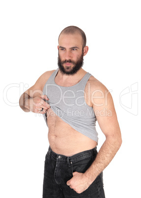 A young bearded man standing in his undershirt