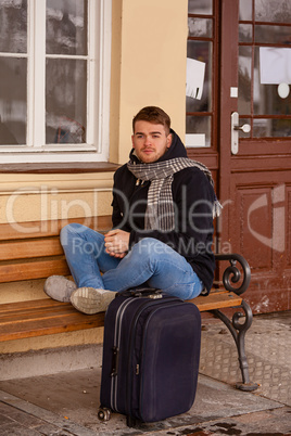 Junger Mann sitzend im Winter auf einer Bank