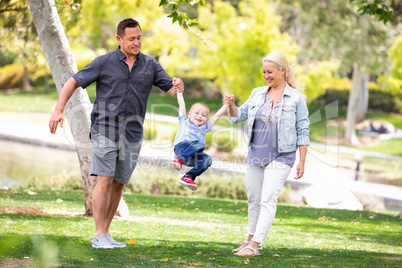 Young Mother and Father Swingging Their Son At The Park