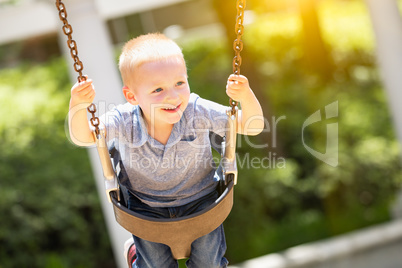 Happy Young Boy Having Fun On The Swings At The Playground