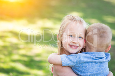 Young Brother and Sister Hugging At The Park