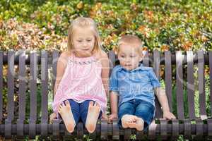Young Sister and Brother Having Fun On The Bench At The Park