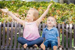 Young Sister and Brother Having Fun On The Bench At The Park