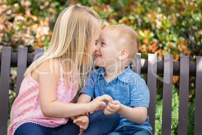 Young Sister and Brother Having Fun On The Bench At The Park
