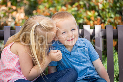 Young Sister and Brother Whispering Secrets On The Bench At The