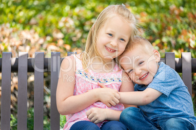 Young Sister and Brother Having Fun On The Bench At The Park