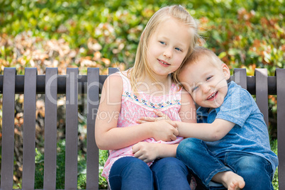 Young Sister and Brother Having Fun On The Bench At The Park