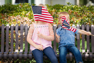 Young Sister and Brother Waving American Flags On The Bench At T