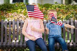 Young Sister and Brother Waving American Flags On The Bench At T