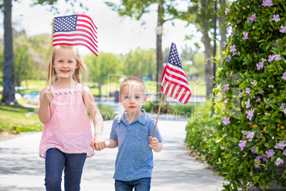 Young Sister and Brother Waving American Flags At The Park