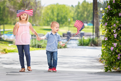 Young Sister and Brother Waving American Flags At The Park