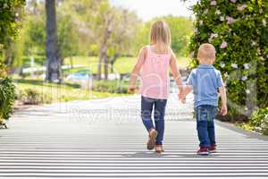 Young Sister and Brother Holding Hands And Walking At The Park