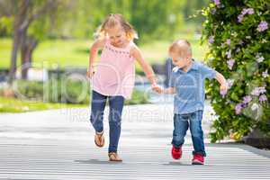 Young Sister and Brother Holding Hands And Running At The Park