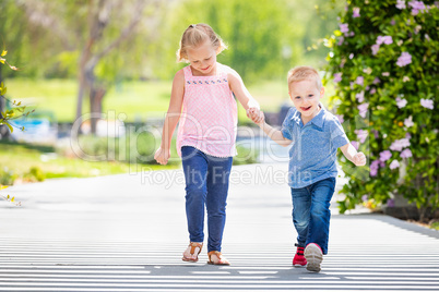 Young Sister and Brother Holding Hands And Walking At The Park