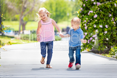 Young Sister and Brother Holding Hands And Running At The Park