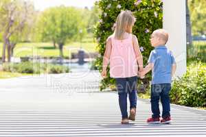 Young Sister and Brother Holding Hands And Walking At The Park