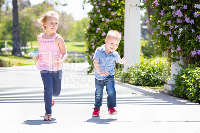 Young Sister and Brother Having Fun Running At The Park