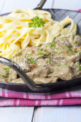 Gebratene Streifen von Fleisch in einer Sahne-Sauce in einer Pfanne