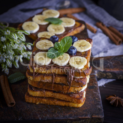 a pile of square fried bread slices with chocolate and banana