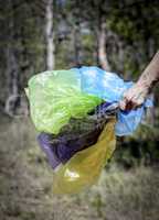 human hand holds many multicolored empty transparent bags for g