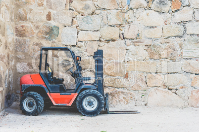 Old, dirty forklift in red on front of wall with copy space for