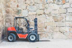 Old, dirty forklift in red on front of wall with copy space for