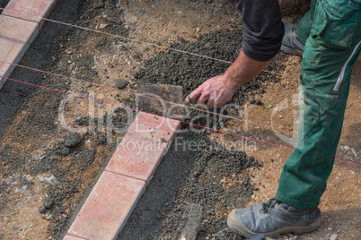 Man is laying paving stones.