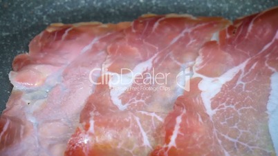 Close up of slices of bacon lays on the hot grill