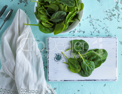 spinach leaves on a white wooden board and in a white ceramic m
