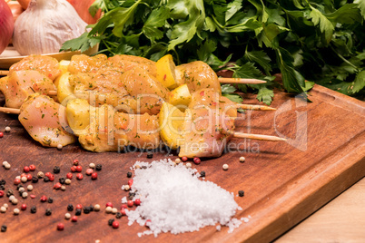 raw chicken skewers marinated with lemon on a wooden board