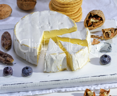 round Camembert cheese on a white wooden board