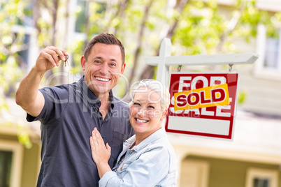 Caucasian Couple in Front of Sold Real Estate Sign and House wit