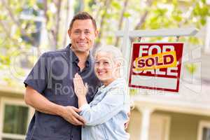 Caucasian Couple in Front of Sold Real Estate Sign and House