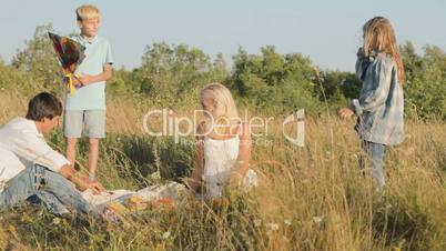 A boy and a girl escape running a kite into the sky and parents watching joyful and smile