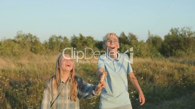 A boy and a girl have launched a kite into the sky and watching joyful