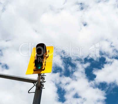 Traffic signal lights against partly cloudy sky.