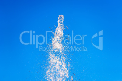 Abstract water fountain splash into clear blue sky.