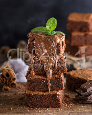 pile of square pieces of baked brownie is poured with chocolate