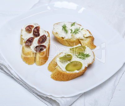 sandwiches with creamy white cheese, sausage, olives and dill