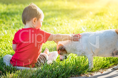 Cute Baby Boy Sitting In Grass Petting Dog