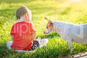Cute Baby Boy Sitting In Grass Playing With Dog