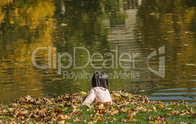 Child Plays With Leaves On A Pond In Autumn