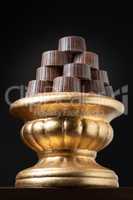 Stack of Fine Chocolates On Golden Pillar Dish With Dark Backgro